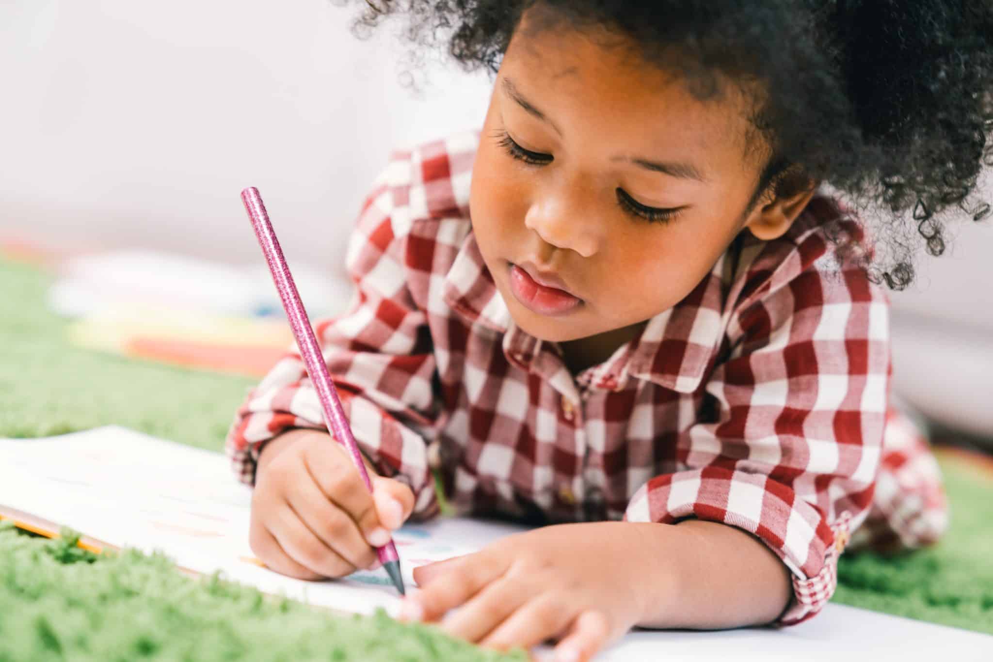 Cute young African American kid girl drawing or painting with colored pencil. Kindergarten children education, back to school, or preschool child study at home concept