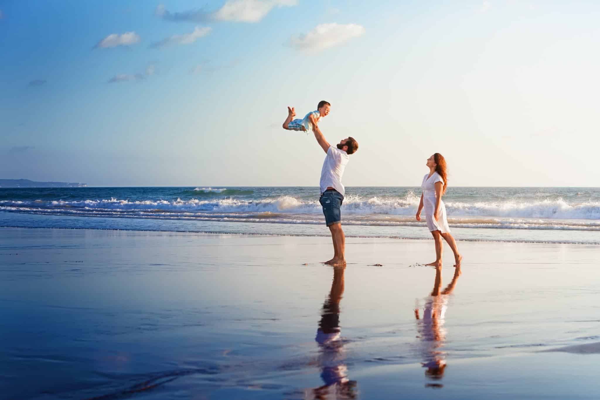 Happy family walking with fun on sunset sea beach