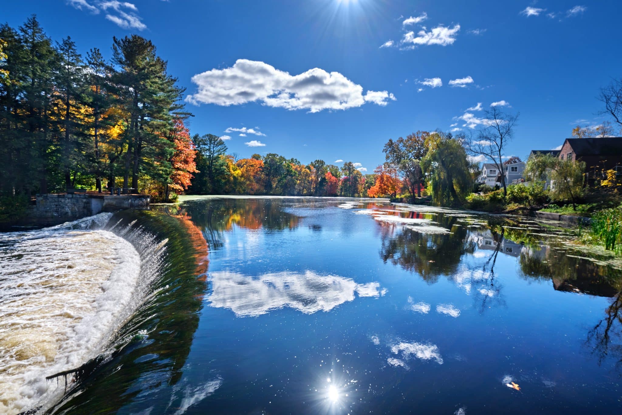 Weir on the Charles River and fall sunshine reflecting in the water at South Natick Dam Park