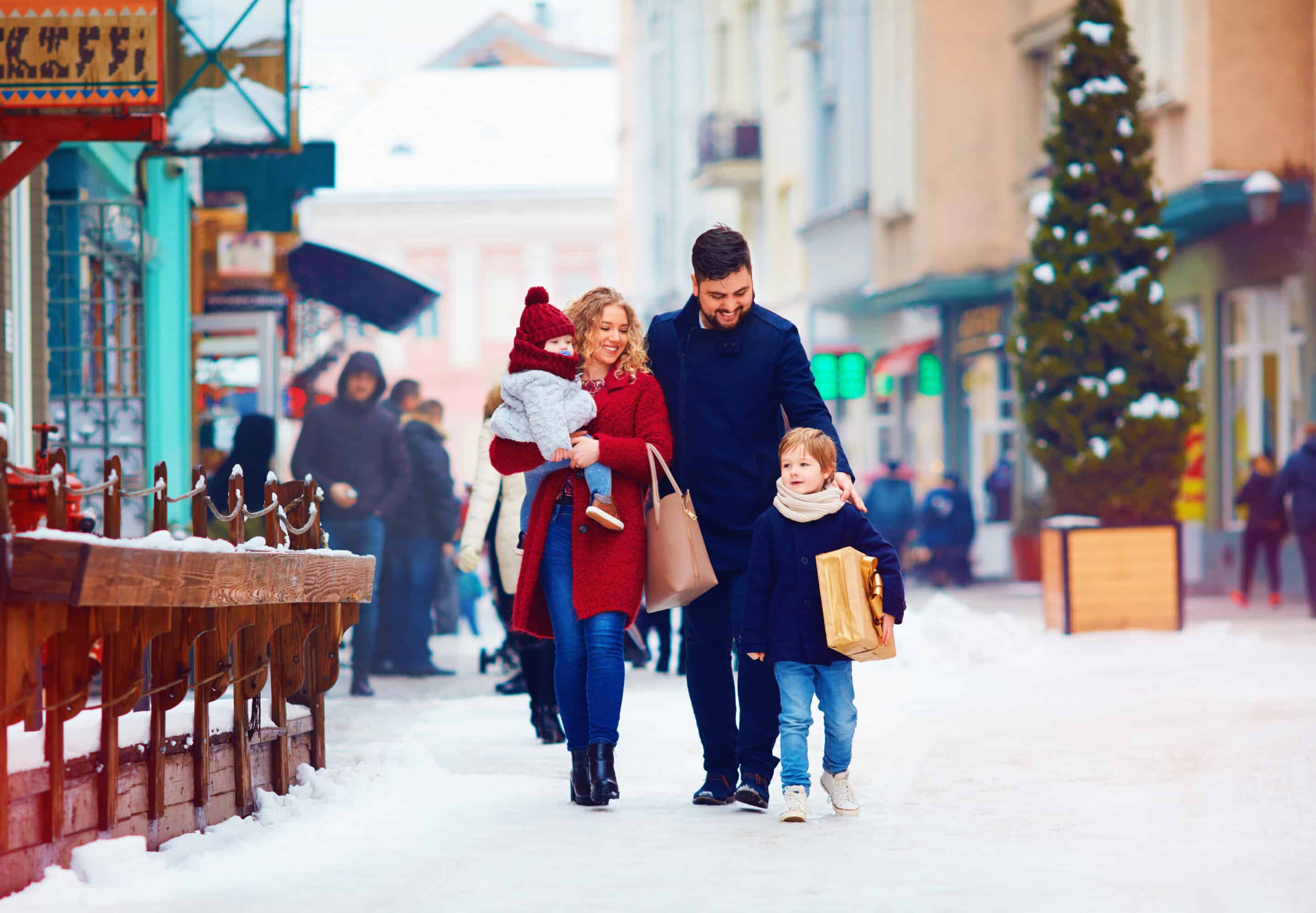 Family Strolling Through a Festive Snowy Downtown Family walking through a snowy downtown street during the holiday season