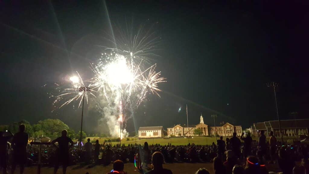 Fourth of July fireworks display in Needham, Massachusetts, with crowds gathered on the field at night